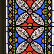 Many of these windows are done in grisaille, a technique whose name comes from the French word for gray, gris. Look closely at the grayish background, and you’ll see that it is composed of small diamond-shaped panes, each hand-painted in the same design using black, gray, or occasionally white enamel on frosted white glass.