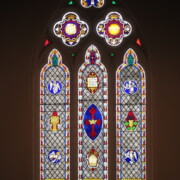 The large compound window behind the altar describes fundamental Episcopal beliefs in three parallel tall windows with pointed tops (lancets) below and three smaller, lobed panels above.